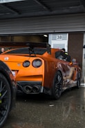 an orange sports car parked in front of a building