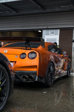 an orange sports car parked in front of a building