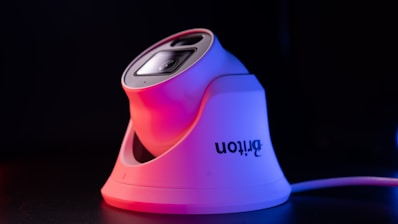 A sleek IP camera mounted on a modern home exterior during sunset.