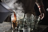 a person pouring a pitcher of liquid into glasses