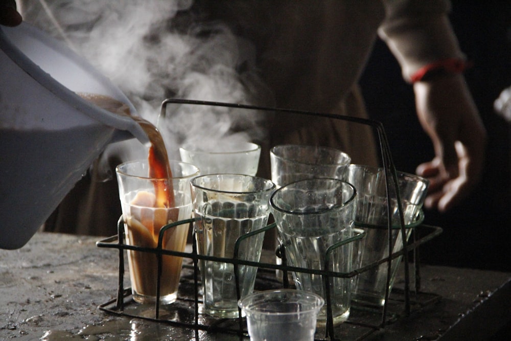 a person pouring a pitcher of liquid into glasses