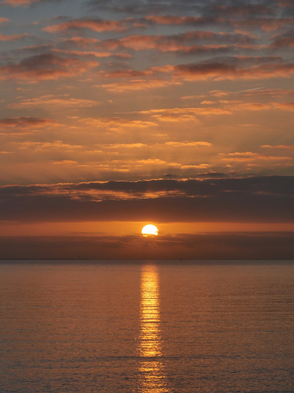 una gran masa de agua con una puesta de sol en el fondo