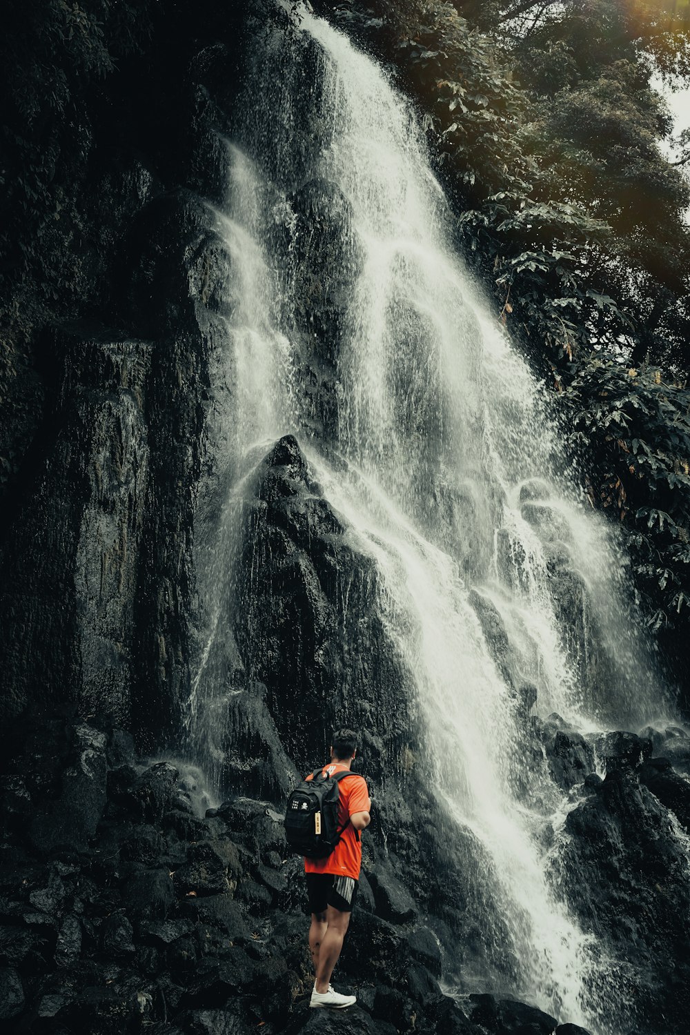 a man standing in front of a waterfall