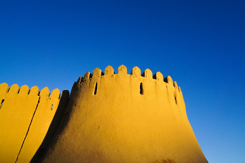 a tall yellow building with a blue sky in the background