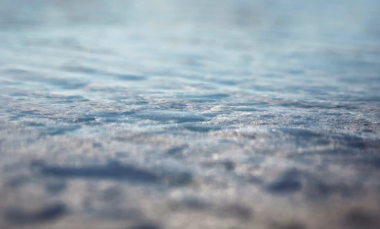 A serene close-up of rippling water reflecting sunlight, evoking calm and clarity.