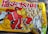 A colorful snack packaging featuring a cartoon character with a red outfit and large eyes. The character has one arm raised, holding a bag, with a sheep-like figure next to it. The packaging displays a mix of Japanese characters in bold red and black colors. The transparent section shows a collection of beige snacks inside.
