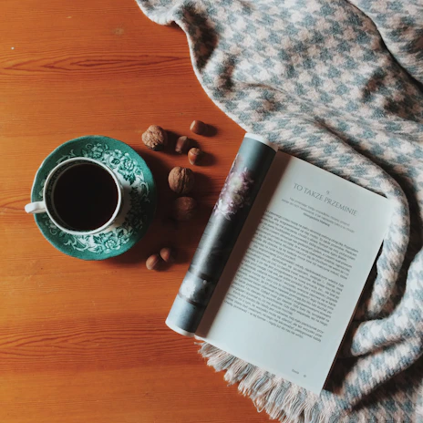 A cozy kitchen scene with a bowl of pecan nuts next to a warm cup of tea on a wooden table.