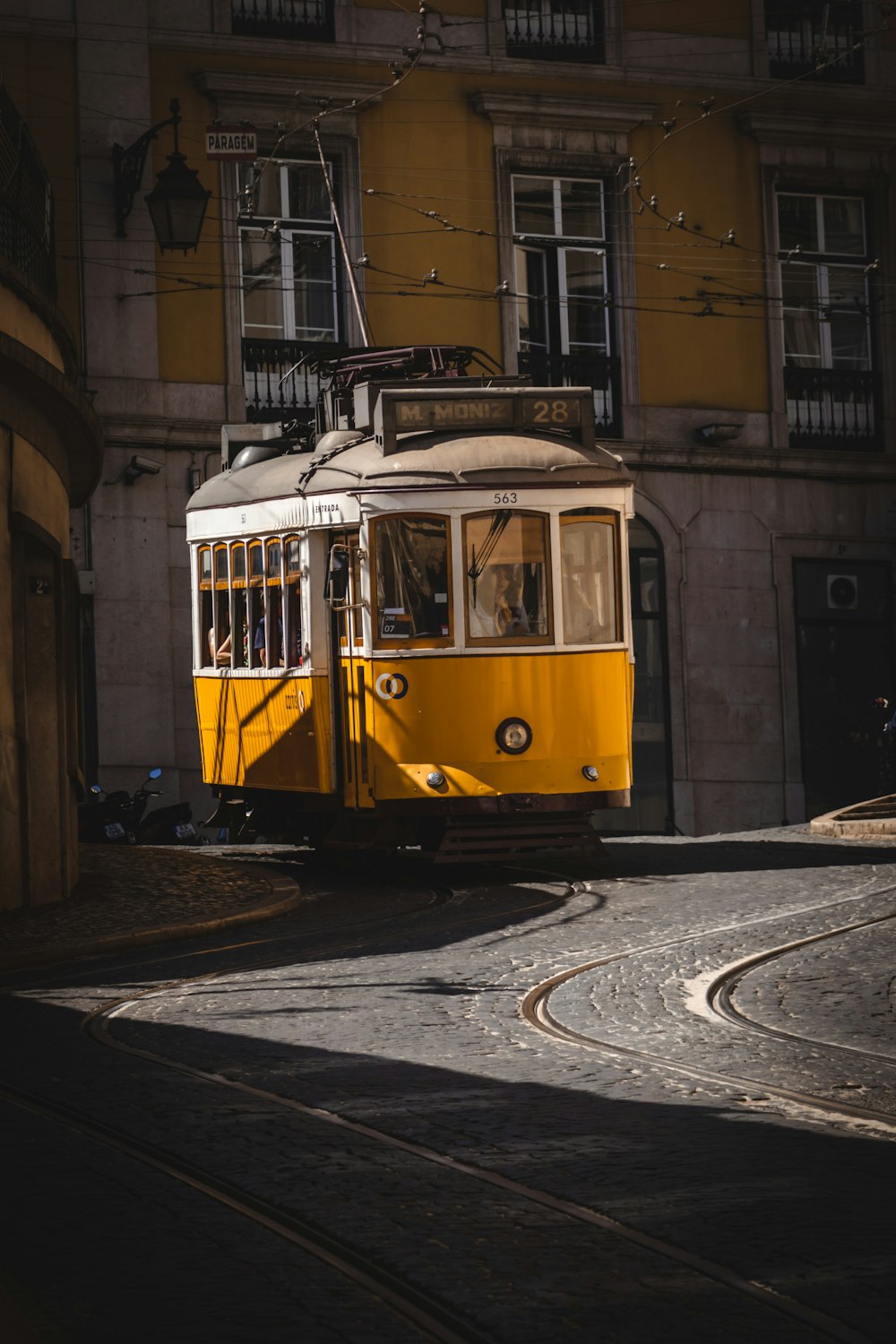 a yellow trolley car traveling down a street next to a tall building