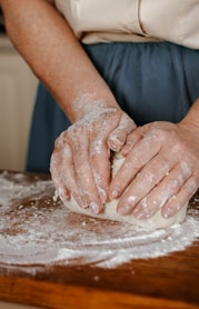 a person kneading dough on top of a wooden table