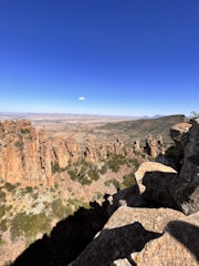 A wide landscape showing geological formations with a clear blue sky.