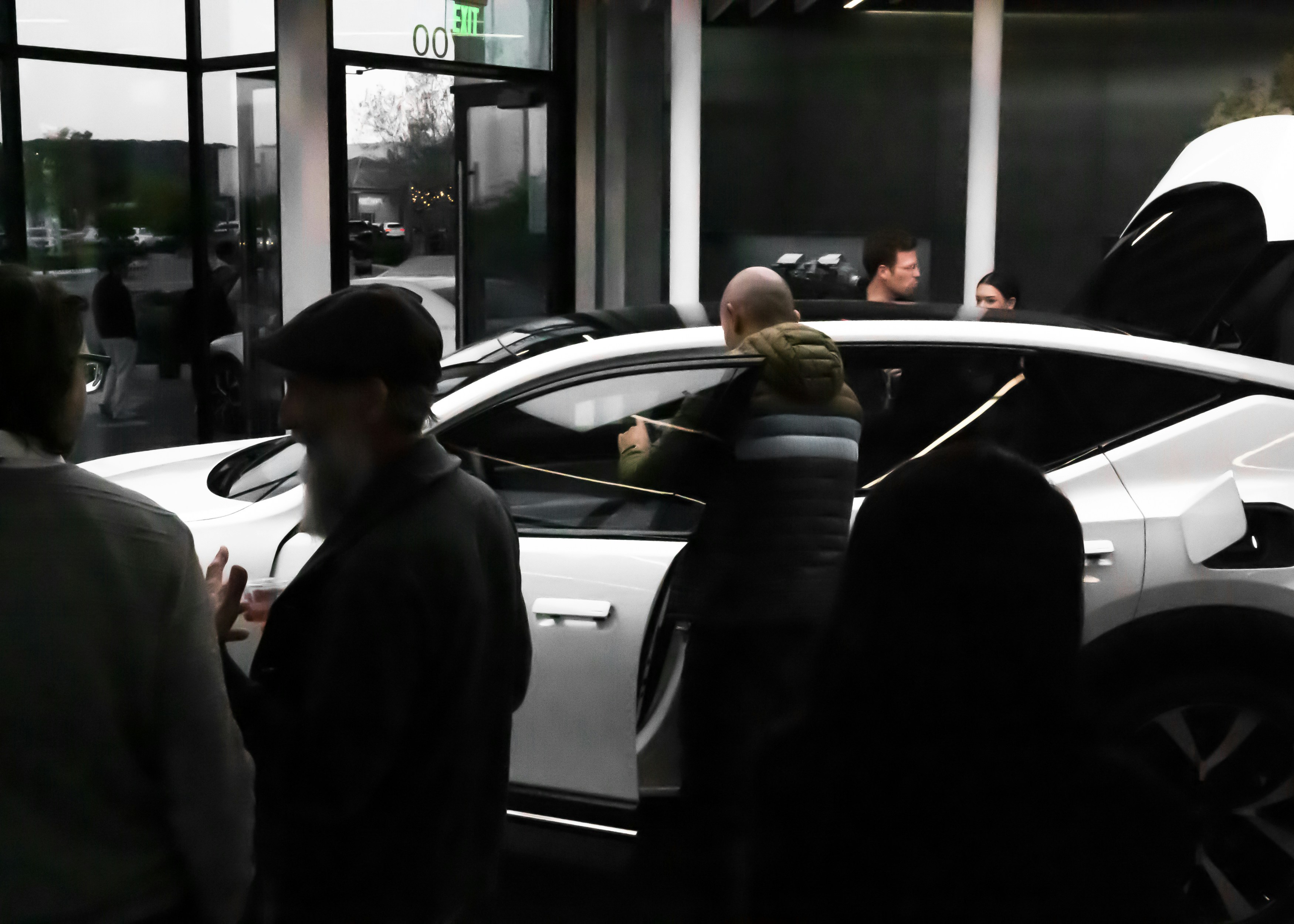 Line of Tesla electric vehicles charging at a Supercharger station at dusk