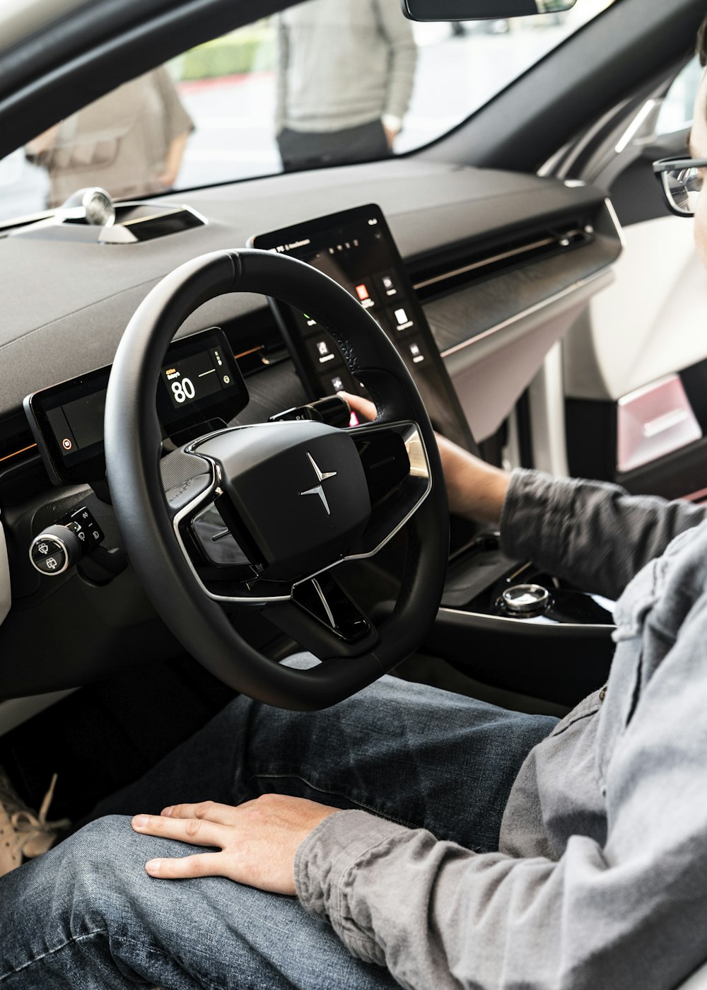 a man sitting in a car with his hands on the steering wheel