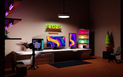 A modern home office setup features two large monitors with vibrant, abstract designs. The room is illuminated by soft, colorful lighting, and a neon sign displaying '2024' is mounted on the wall. There is a computer tower on the desk and shelves with various decorations, including a small plant and glowing orbs in a shelving unit. A chair and a potted plant are situated on the wooden floor.