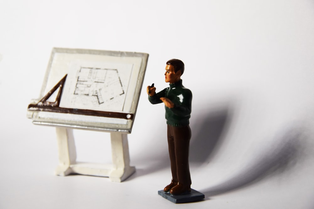 a toy man standing next to a miniature easel