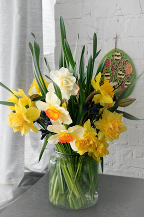 Close-up of a modern artificial daffodil arrangement in a sleek white vase.