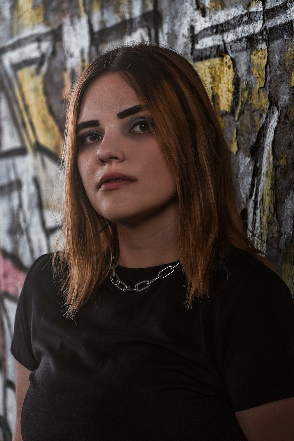 a woman standing in front of a wall with graffiti on it