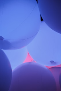 Soft glowing orbs of pink, blue, and purple light floating gently in a dark serene space.