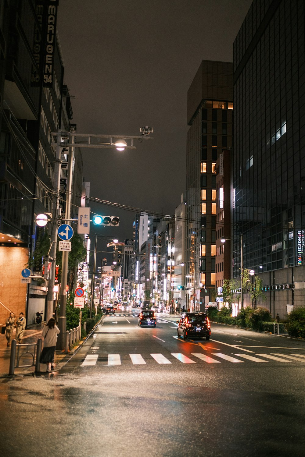 a city street at night with cars driving down it