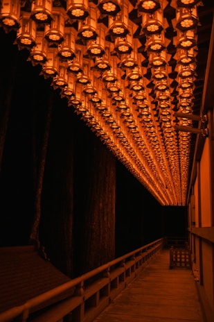 A dark hallway lined with flickering lanterns casting long shadows.