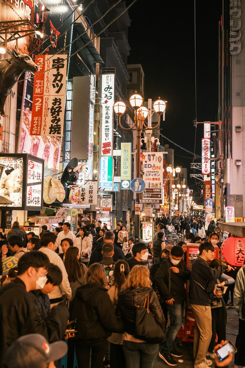 a crowd of people walking down a street next to tall buildings