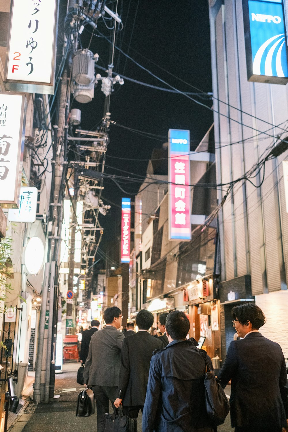 a group of people walking down a street next to tall buildings