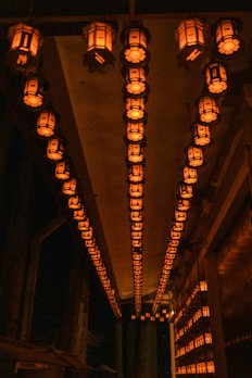 A hallway illuminated by a series of elegant bamboo wall lanterns creating a peaceful path.