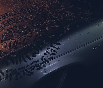 A craftsman applying vibrant vehicle lettering on a company van under bright daylight.