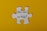 A large white puzzle piece is centered against a bright yellow background. The text 'How can we help?' is written in black, elegant script on the puzzle piece.