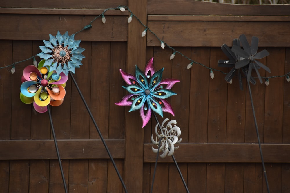 three paper flowers are hanging on a fence