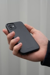 Close-up of hands holding a smartphone with a neutral pastel-colored case.