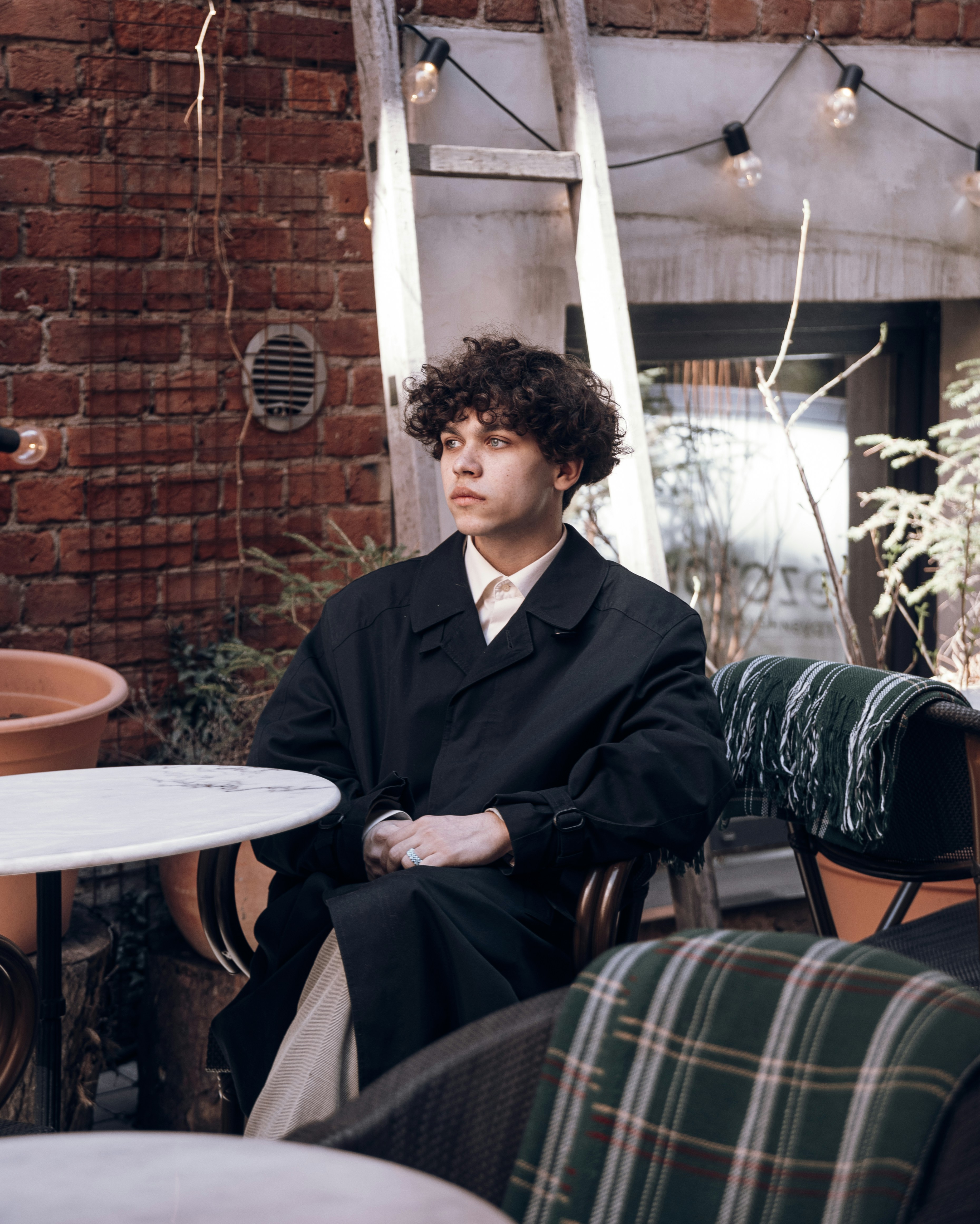 a man sitting in a chair next to a brick wall