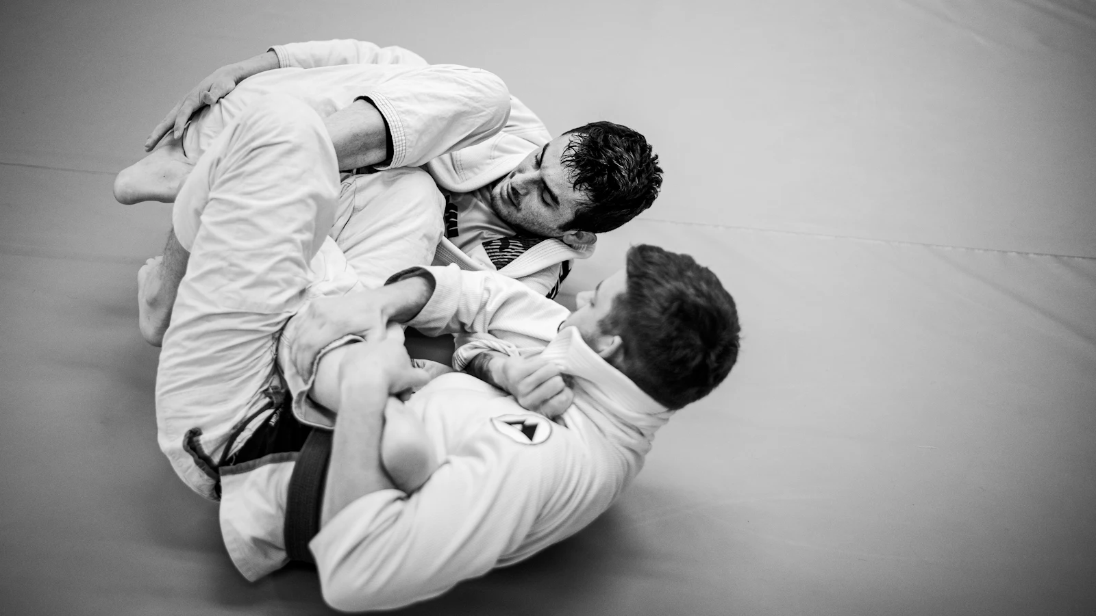 Luta de jiu-jitsu no solo, quimonos em preto e branco