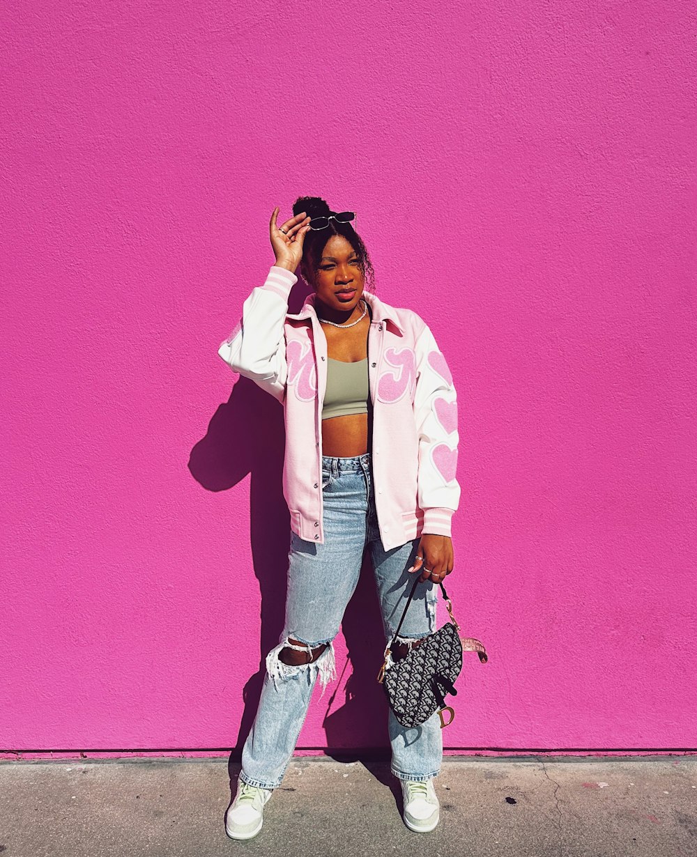 a woman standing in front of a pink wall