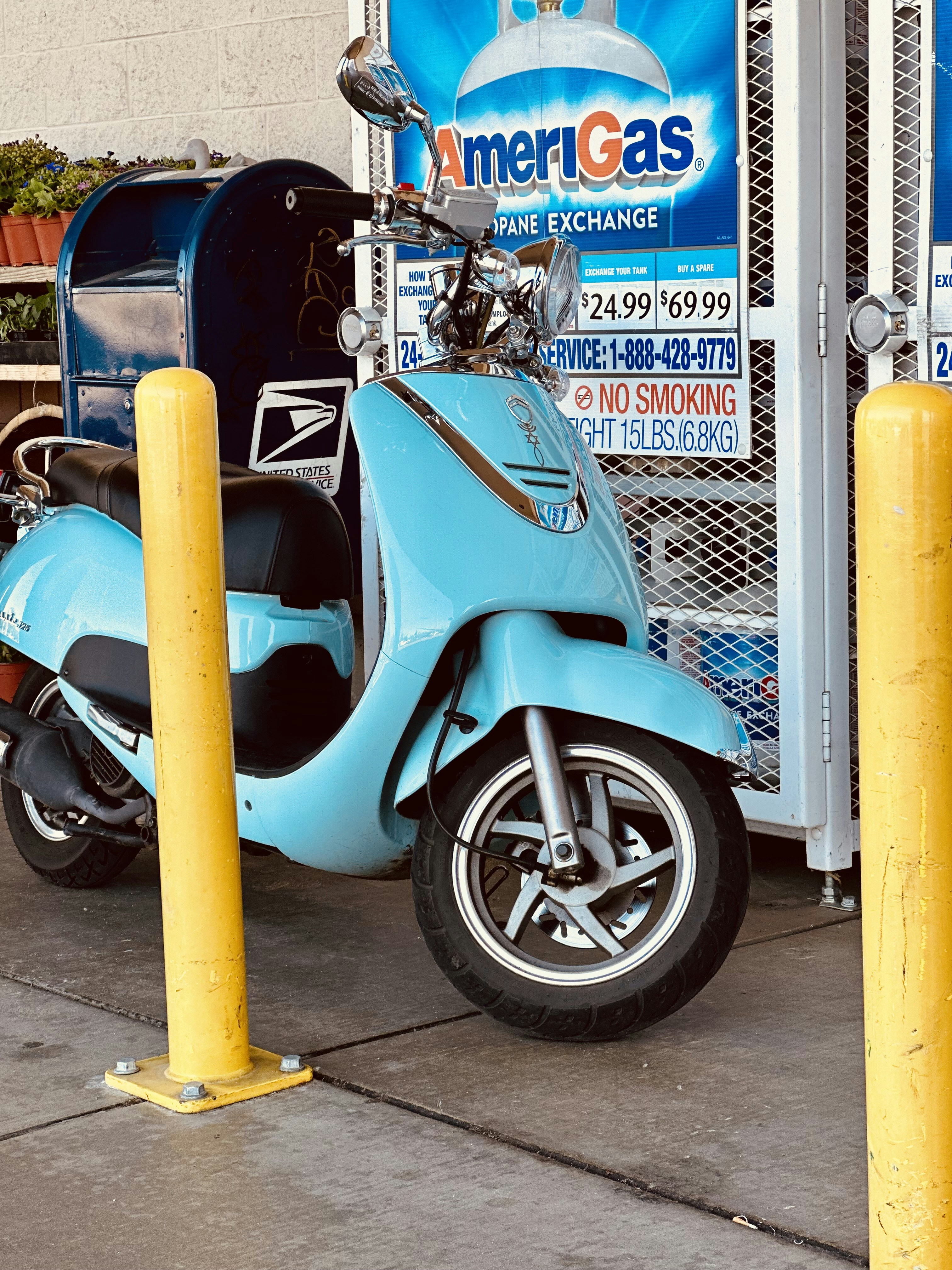 a blue scooter parked next to a yellow pole