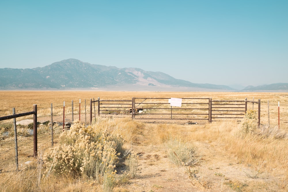 a field with a fence and a sign in the middle of it