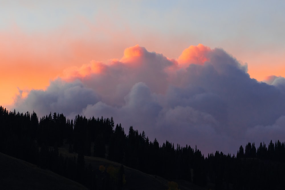 a sunset view of some clouds and trees