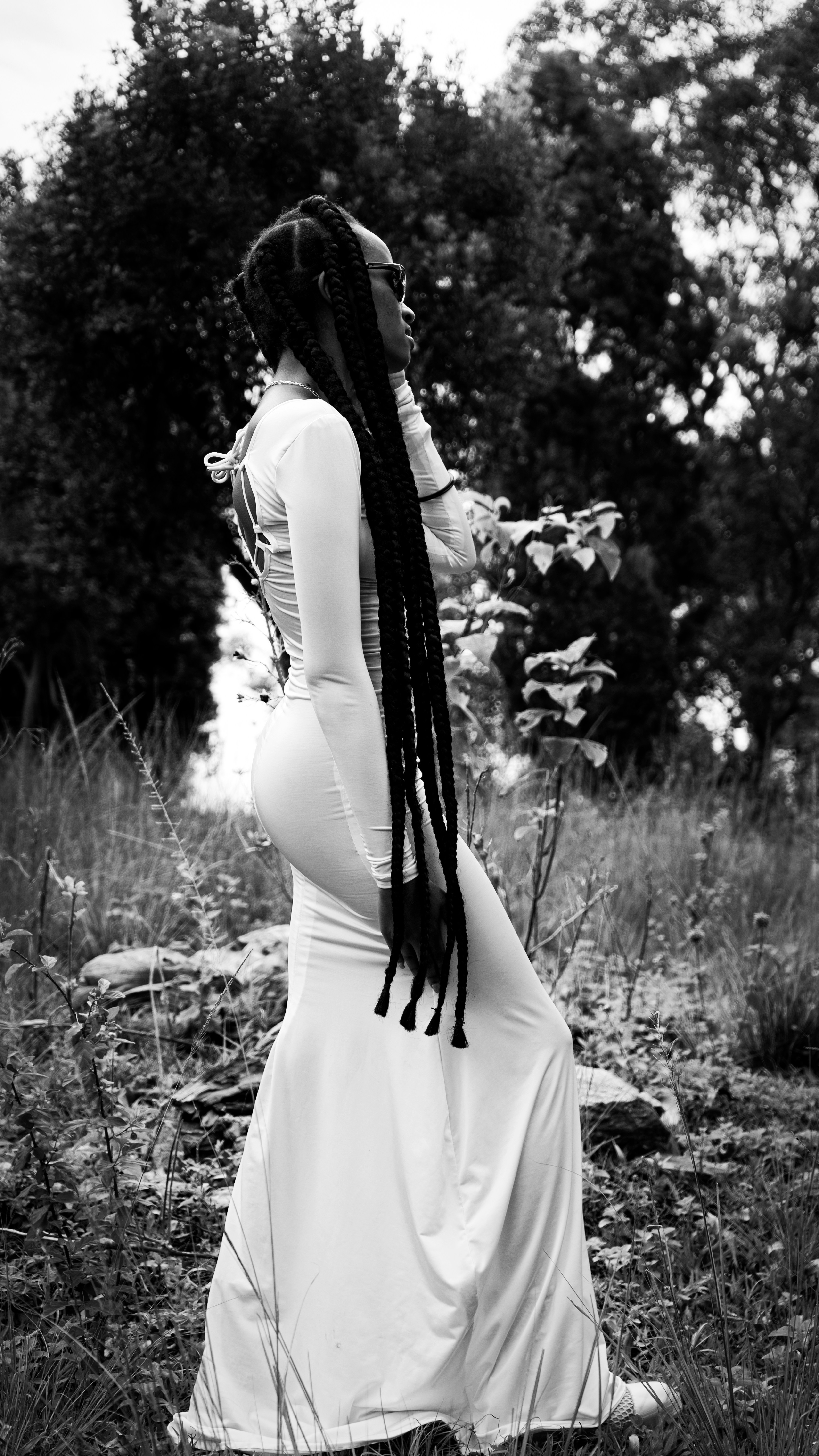 a pregnant woman in a dress standing in a field