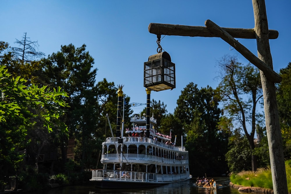 a large boat floating down a river next to a forest