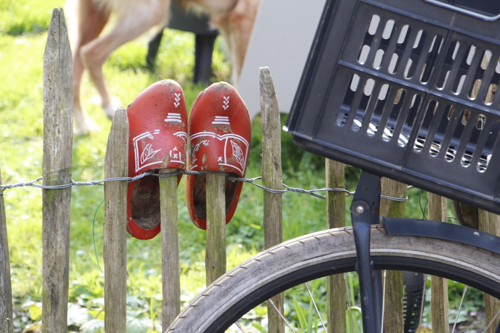 a pair of red shoes are hanging on a fence