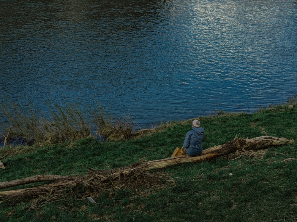 a person sitting on a log near a body of water