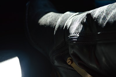 A close-up of a richly detailed black leather boot with gold embroidery, resting on a polished marble floor.