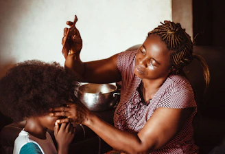 A cozy braiding shop interior with a stylist working on a client's hair.