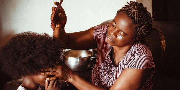 A cozy braiding shop interior with a stylist working on a client's hair.