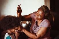 Close-up of hands expertly braiding natural curly hair with warm lighting.