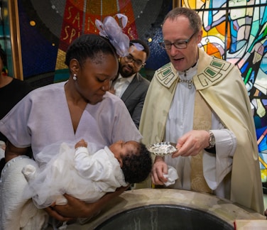 a priest feeding a baby a piece of cake