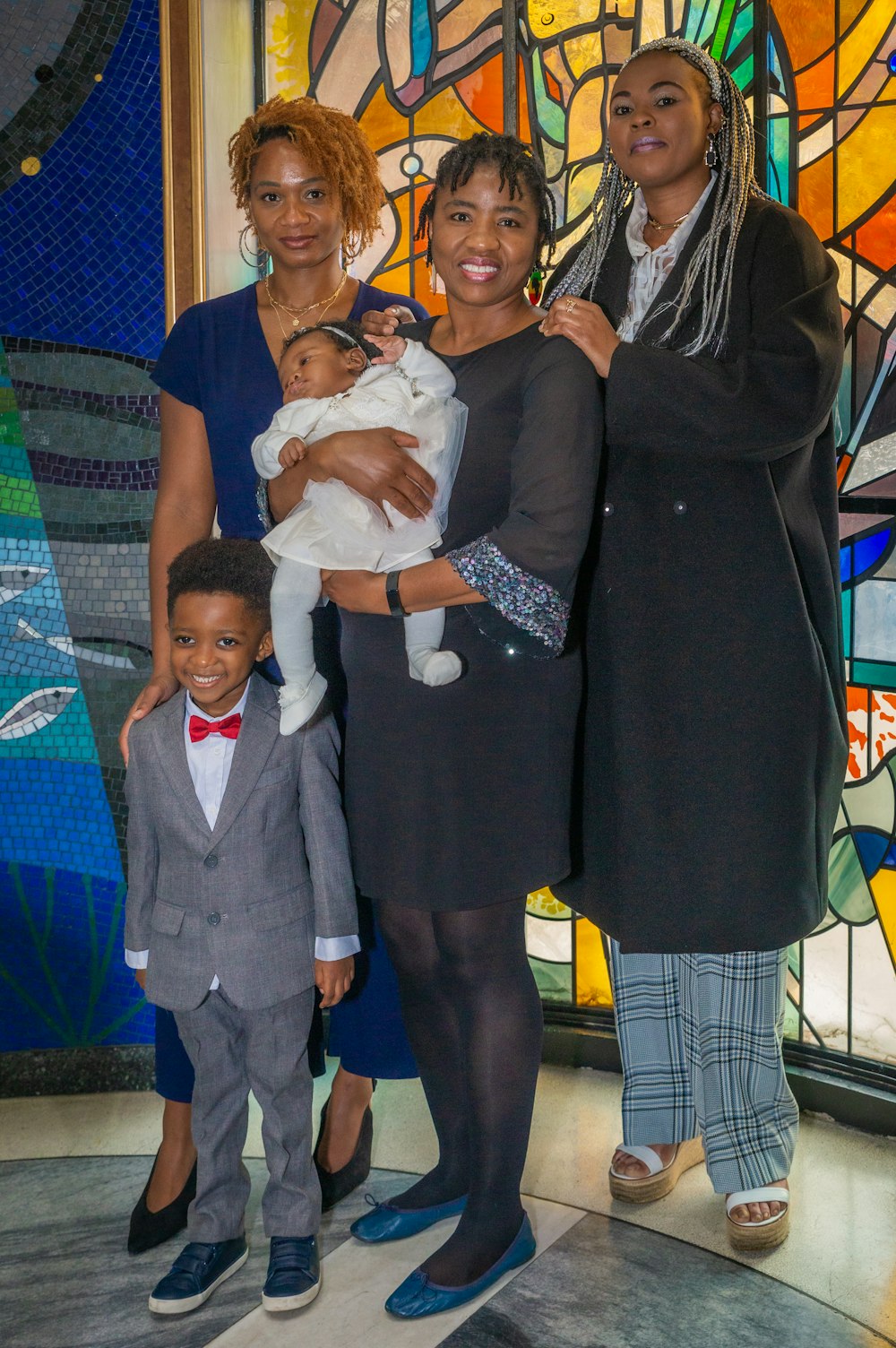 a group of people standing next to each other in front of a stained glass window