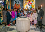 A joyful baptism celebration with family gathered around a decorated altar.