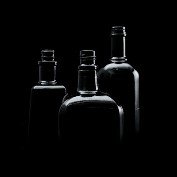 A sleek collection of soda, coffee, and juice bottles with dark backgrounds and golden highlights.
