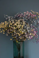 A tall vase filled with vibrant wildflowers in soft pastel tones against a muted background.