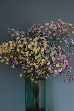 A close-up of fresh wildflowers in shades of green and gold, arranged in a simple, elegant vase.